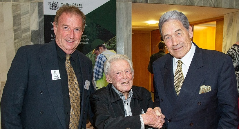 Three men in suits stand beside each other - on the left is senior heritage advisor for the Department of Conservation Paul Mahoney, the man in the middle is the oldest ex-Forest Service employee at the event, Jim Speirs, and the man on the right is deputy Prime Minister Winston Peters. Mr Speirs is shaking the deputy Prime Minister's hand.