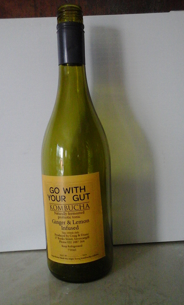 A glass bottle of kombucha, ginger and lemon flavour.