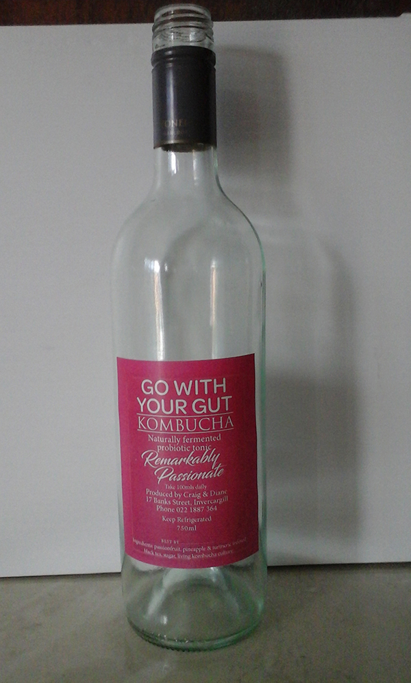 An empty glass bottle of kombucha with a label showing the remarkably passionate flavour.
