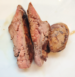 A well cooked chicken liver, cut in half to show it is pink in the middle.