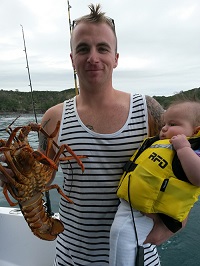 Kyall, off-duty, holding a crayfish in one hand, and his baby boy in the other.