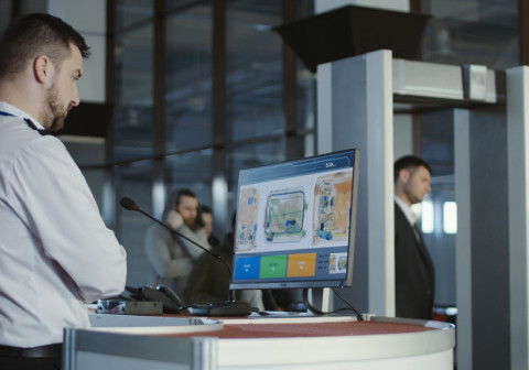 Airport worker examining x-ray of baggage.