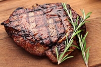 steak with rosemary on a wooden cutting board